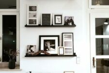 a super elegant gallery wall with black ledges, black and white artworks and books is a chic option for a modern space