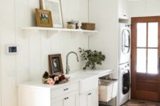 a white farmhouse mudroom laundry with shaker cabinets, stacked appliances, an open shelf and a basket