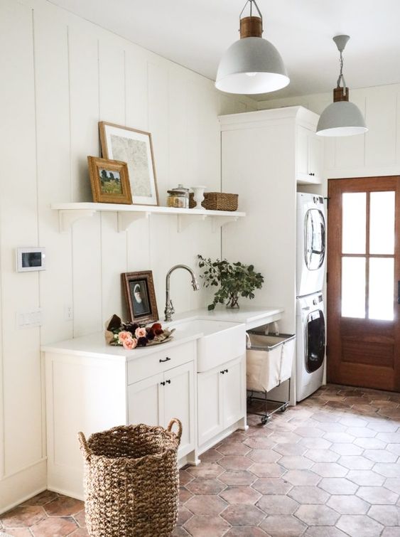 a white farmhouse mudroom laundry with shaker cabinets, stacked appliances, an open shelf and a basket