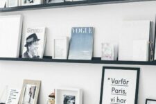 a white wall and contrasting black ledges, books, artworks, decorative plates and even funny toys personalize the space a lot