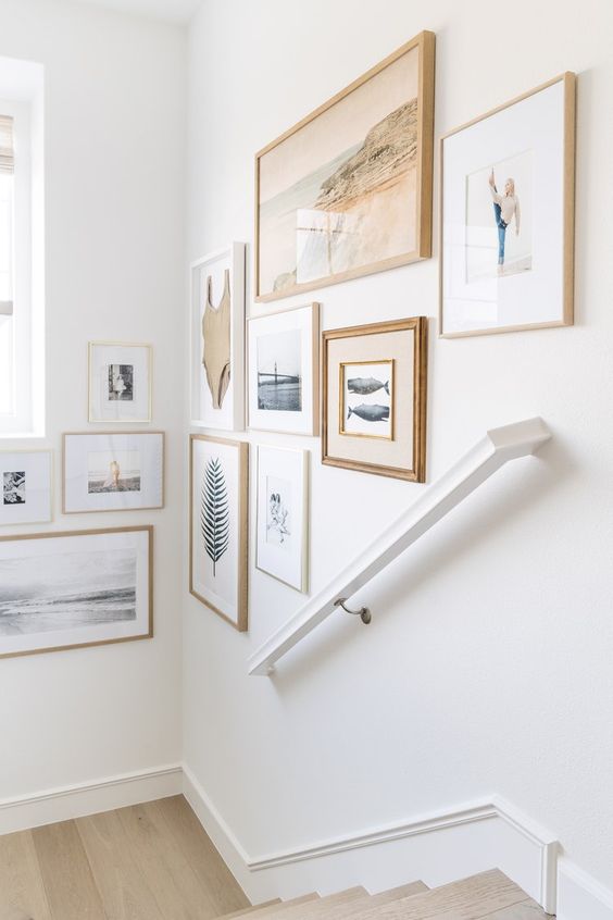 An airy gallery wall that takes several walls and shows off beautiful art and photos, with light stained and white frames