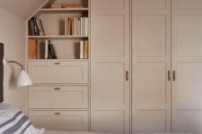 an attic bedroom with a blush accent wall and blush wardrobes and drawers built in is a lovely and welcoming space