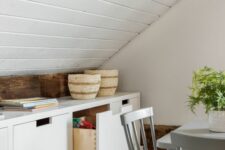 an attic nook with a large white storage unit with drawers, some baskets and potted greenery is amazing
