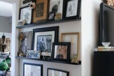 an awkward nook with black ledges and various colored and black and white art in black frames and some more art hanging over the ledges