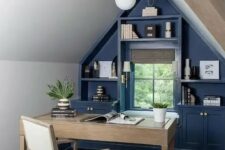 an elegant farmhouse attic home office with a blue accent wall with built-in storage, a stained desk and a neutral chair, pendant lamps
