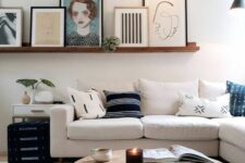 an elegant modern living room with a neutral sofa and pillows, a wooden coffee table, a stained ledge with artworks