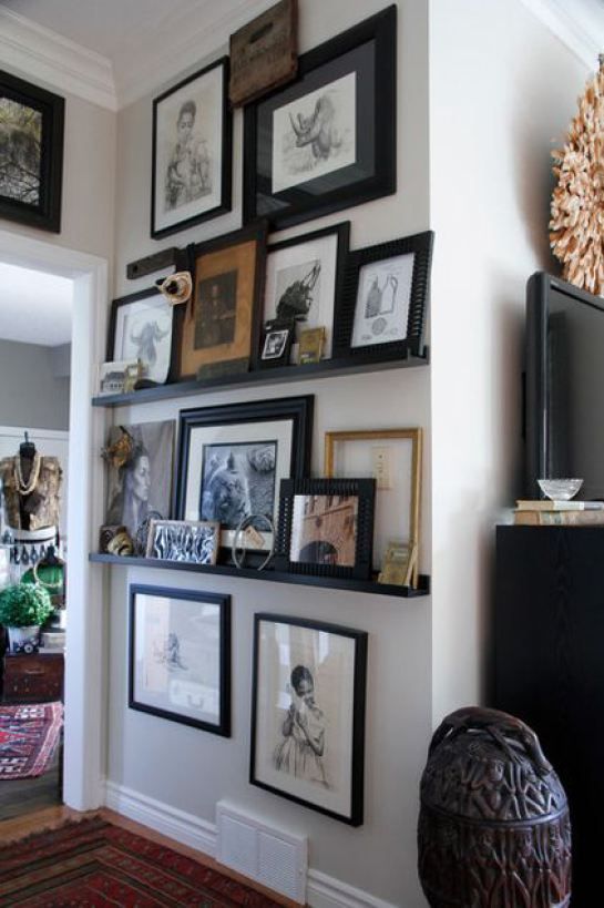 a gallery wall with black ledges, mismatching artwork in different styles, with different black and stained frames is a cool farmhouse space