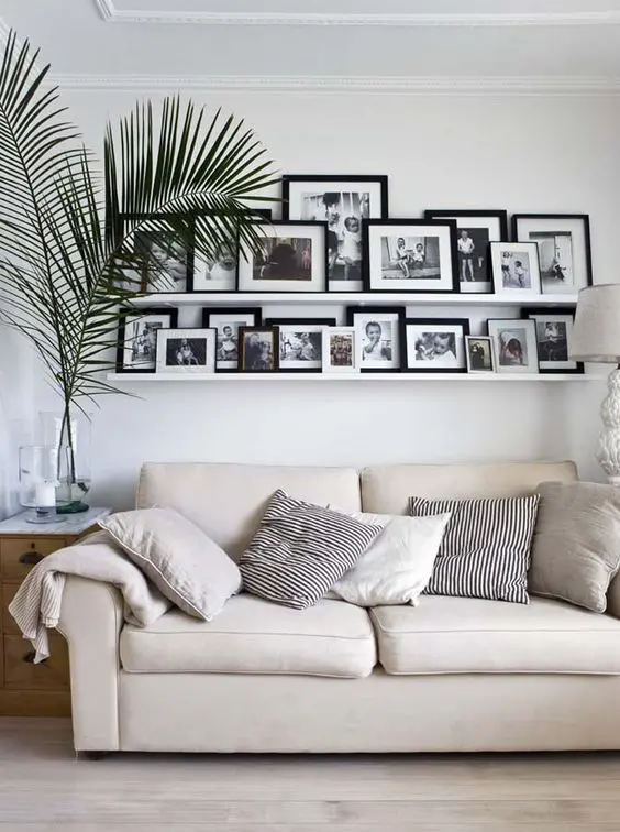 a laconic gallery wall with white ledges and black and white family pics is a nice solution for a modern or Scandinavian space