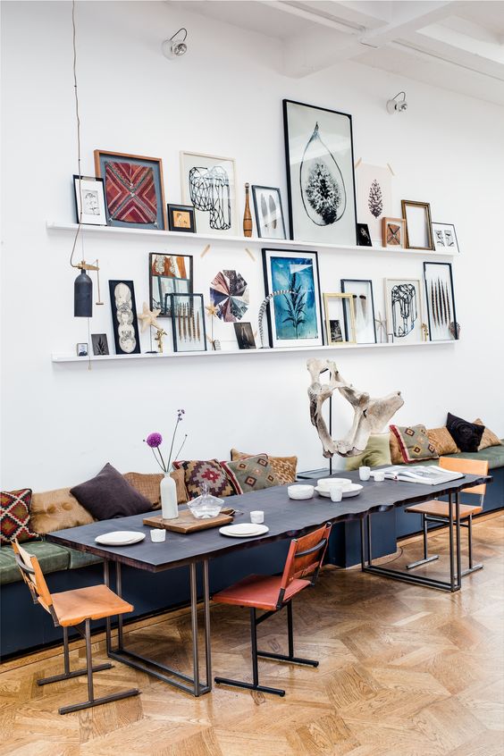 a very eye-catching and eclectic gallery wall with white ledges, colorful and graphic artwork, botanical and ethnical pieces is a cool idea