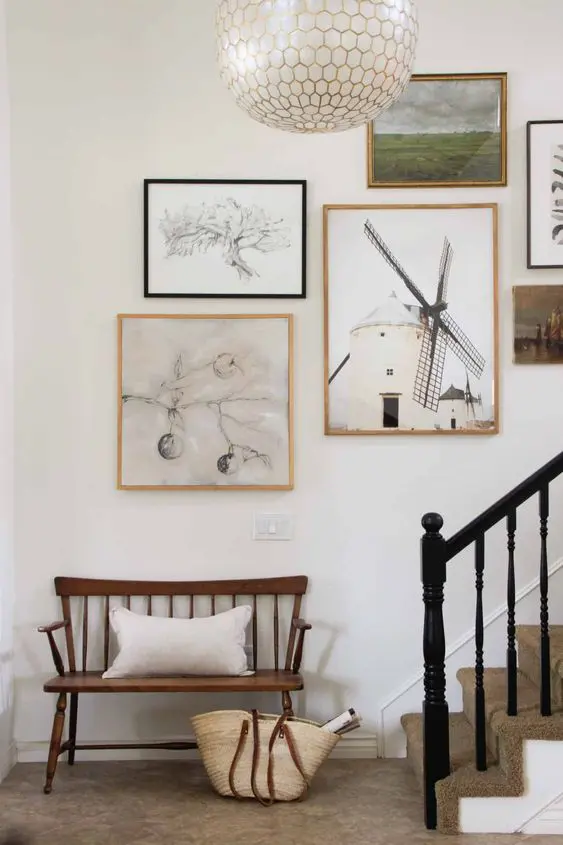 this beautiful gallery wall over the stairs features mismatching frames and lots of graphic artworks