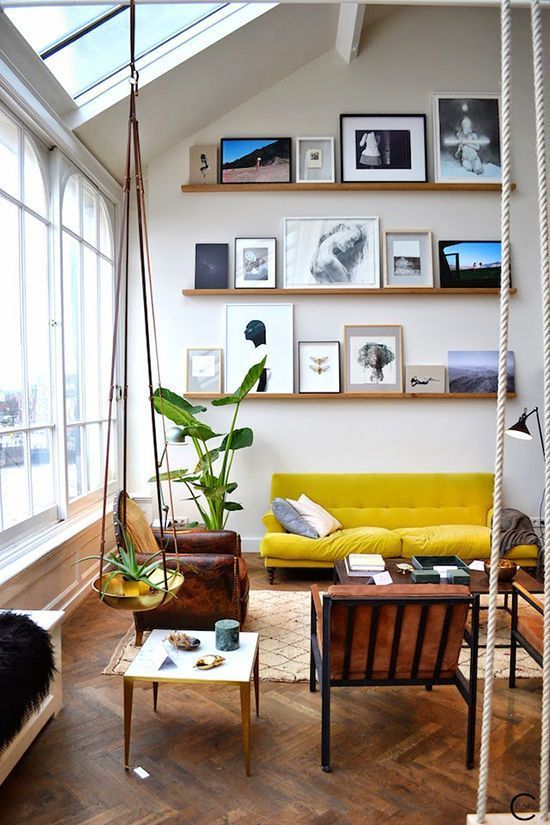 an airy gallery wall with stained ledges and black and white photos and artwork is a cool and stylish solution for a modern space