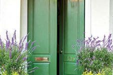 22 sage green door with brass numbers and potted greenery around