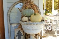 16 corn stalks and a pumpkin arrangement in a vintage urn