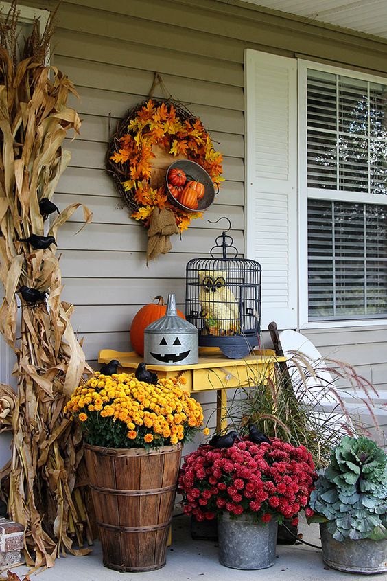 a leaf wreath, corn husks, mums and pumpkins