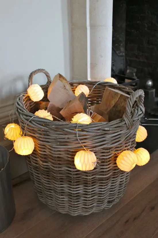 a basket with firewood and paper lights shaped as pumpkins is a cool idea for a rustic space