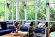 a bright screened patio with wicker seating furniture with navy upholstery, a low coffee table and some blooms and lanterns