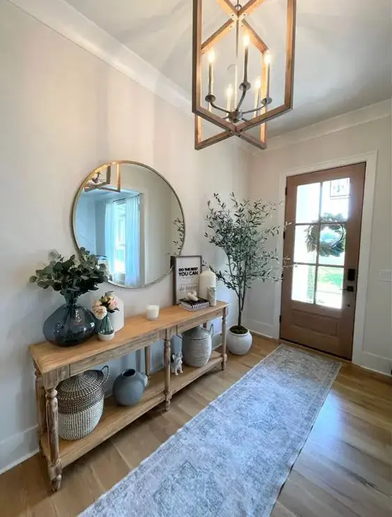 a classic modern farmhouse entryway with a console table, a round mirror, some baskets and vases plus a potted plant