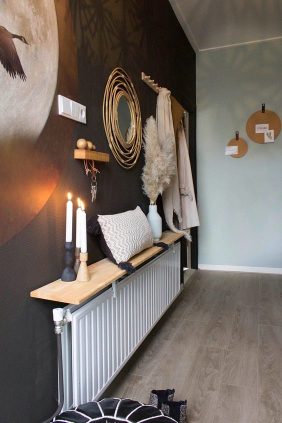 a long radiator with a long and narrow shelf used for decor, candles, a pillow and pampas grass