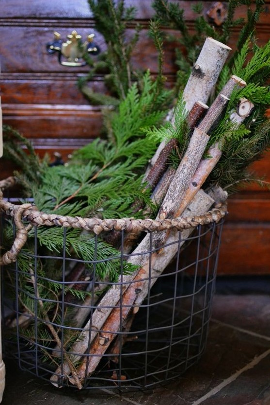 a metal basket with branches and evergrens for decorating a porch for winter or Christmas