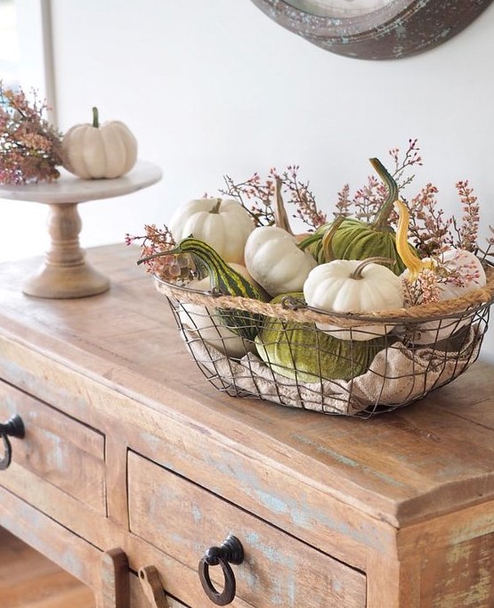 a metal basket with real and velvet pumpkins and gourds and some wildflowers is a gorgeous display for the fall