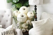 a metal wire basket fulled with white pumpkins and greenery for a vintage-inspired space