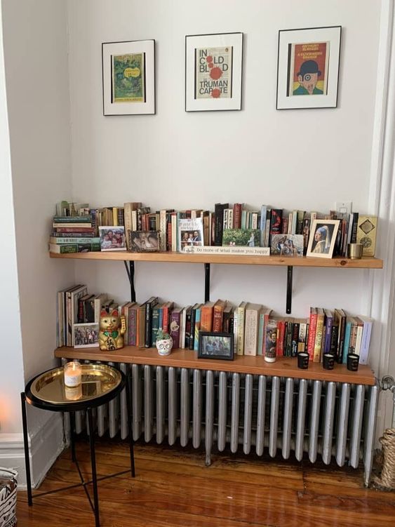 a metallic radiator with two stained bookshelves over it, one of them completely covers the radiator and makes it part of decor