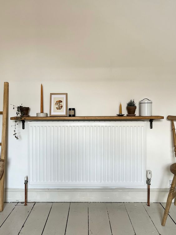 a minimal space with a long and narrow radiator and a stained shelf with candles and decor is cool