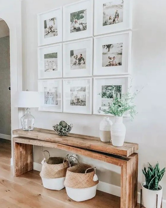 a modern farmhouse entry with a grid gallery wall, a stained bench and baskets, some lovely vases with greenery