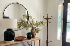 a modern farmhouse entryway with a stained console table, a couple of baskets, some lovely vases, a mirror and a rack