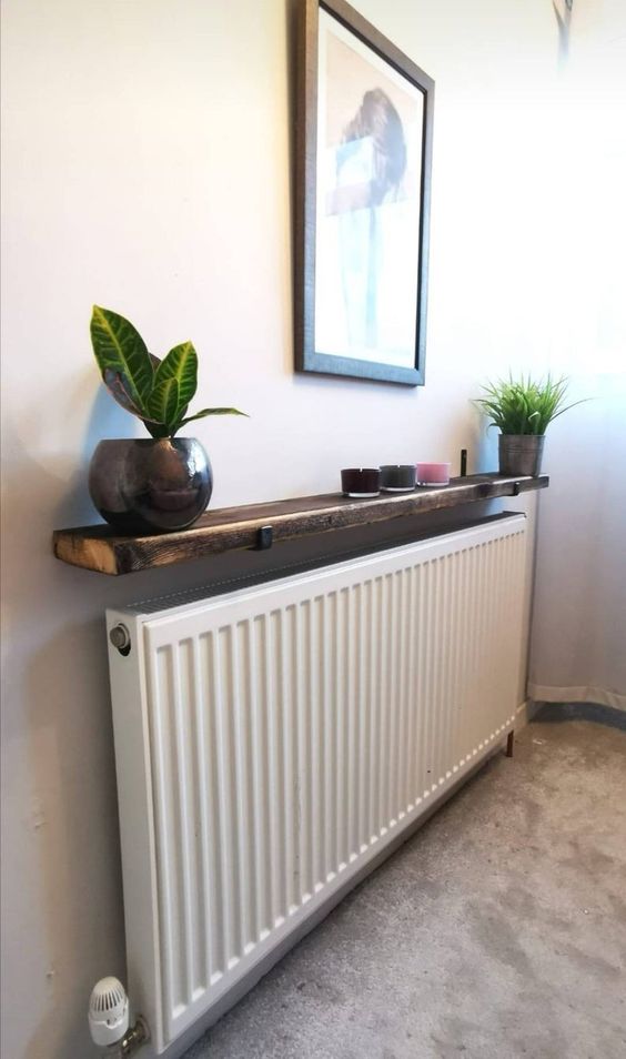 a narrow and long radiator with a dark stained shelf, candles and potted plants is amazing for a modern space