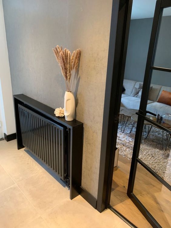 a small black radiator covered with a black shelf over it, with some decor is a cool and lovely idea