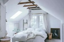 a welcoming modern country bedroom with an attic ceiling and wooden beams, a bed, a window and a skylight, potted plants and a basket