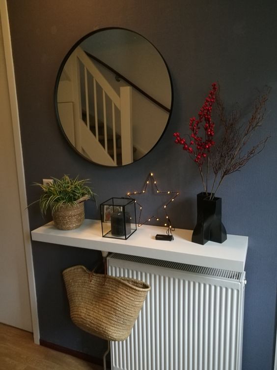 a white radiator covered with a white shelf with some stylish Scandinavian decor is awesome