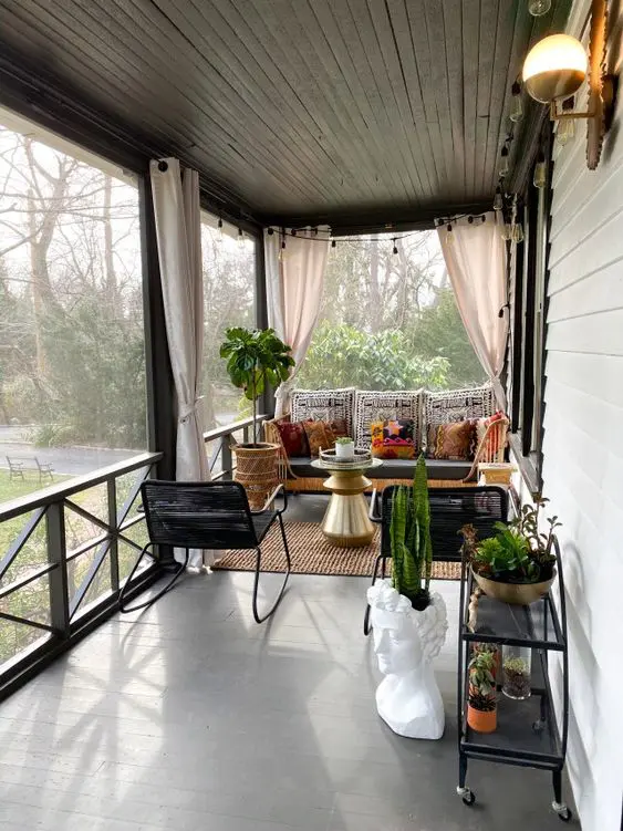 an eclectic screened porch with a sofa, a woven chair, a gold side table and potted plants in unique planters