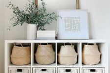 an entryway console table with baskets and white wicker cubbies allows storage without cluttering