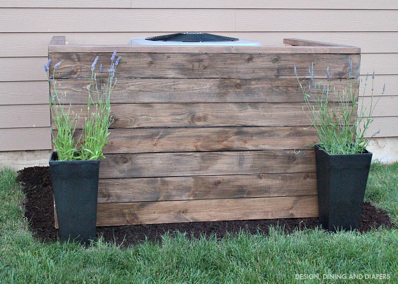 DIY weathered wood AC unit cover with potted flowers