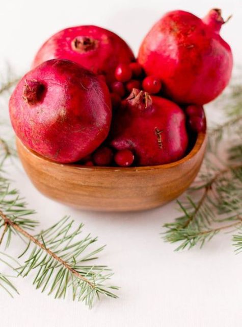 put pomegranates and cranberries in a wooden bowl for a centerpiece