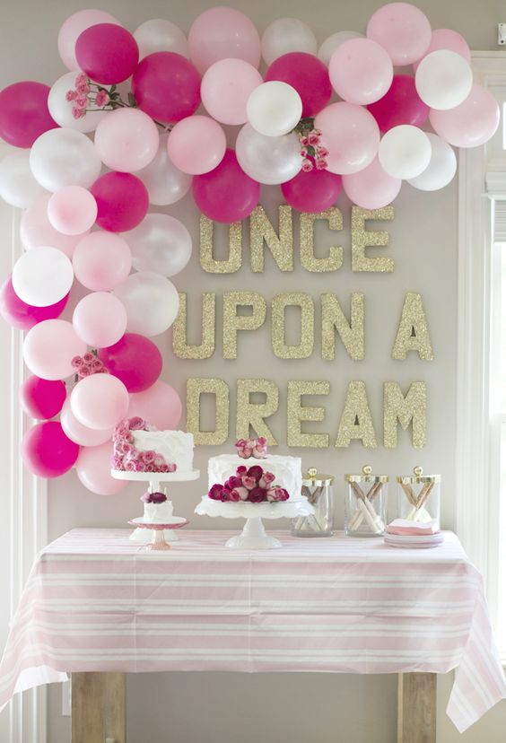 dessert table decorated with a balloon arch and with floral cakes
