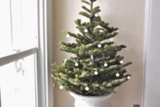 an elegant Christmas tree in an urn and with white ornaments is a very chic and refined vintage-inspired decor idea