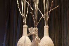 10 frosted wine bottles with white branches, yarn, candles and pinecones