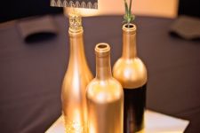 17 gold and glitter wine bottles with candles on a mirror