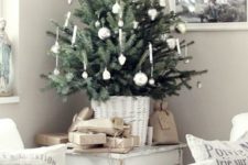 a small tabletop Christmas tree in a white basket and with white ornaments will be great for a chic and neutral holiday space