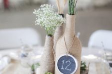 22 totally wrapped yarn bottles with spikes and herbs, a chalkboard table number on a wood slice