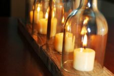 26 cut wine bottles used as cloches for candles and a wooden board to hold them all