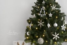 a Nordic tabletop Christmas tree styled with white snowflakes, stars and baubles, lights and a white cover