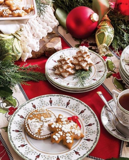 a bold Christmas tea party table with gingerbread cookies, printed porcelain, red textiles and evergreens
