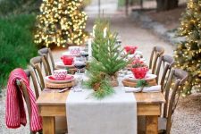 a bold and cool Christmas tablescape with a neutral runner, tree slice placemats, tabletop Christmas trees and red and white bowls