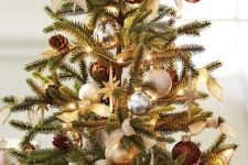 a mini Christmas tree decorated with silver, grey, gold and brown ornaments and lights