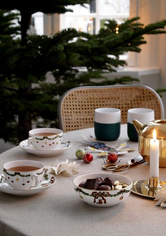 a simple and modern Christmas tablescape with printed teaware, cups, candles and a tea pot plus some ornaments on the table
