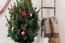 a small Christmas tree in a basket and with silver and red ornaments is a cool and catchy decoration